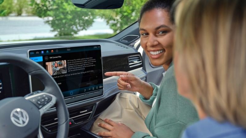 Deux femmes assises à l’intérieur du véhicule en interaction avec l’écran de la VW Passat.