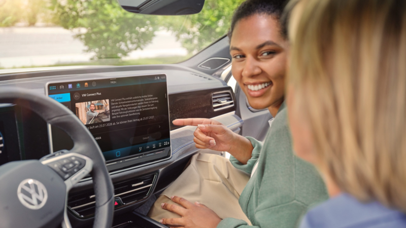 Two women in the interior of the car interacting with the display of the VW Passat.