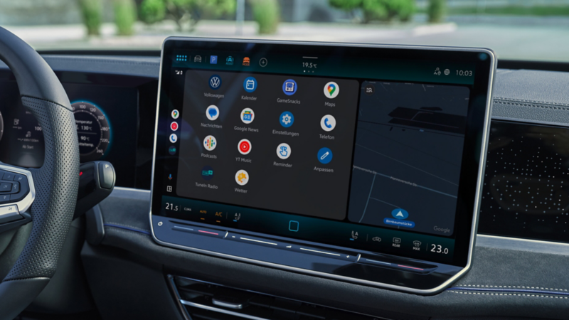 Vue détaillée du poste de conduite d’une VW Passat. Une personne assise sur le siège du conducteur tient un smartphone à la main.