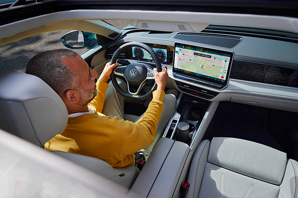 Una persona alla guida di Volkswagen Passat vista dal tettuccio scorrevole aperto.