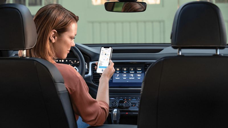Une femme assise dans un véhicule Volkswagen regardant l’application Car-NetMD