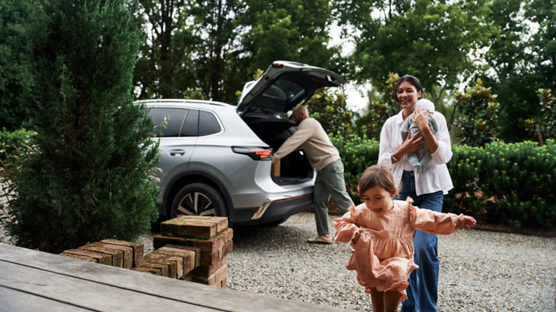 parents and child in the foreground with the new Tiguan in the background. 