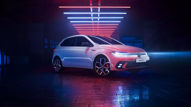 Inquadratura di Polo GTI bianca con fari LED accesi, in uno spazio buio sotto elementi luminosi