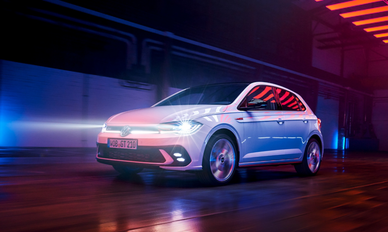 Polo GTI in movimento all'interno di un edificio industriale con i fari accesi