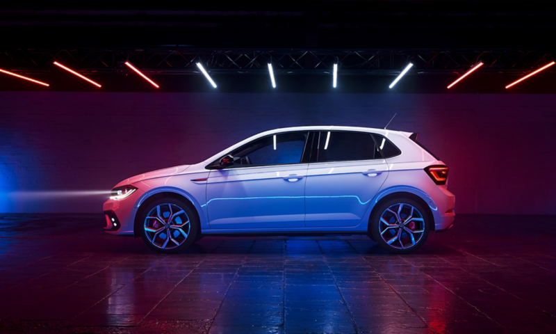 Scatto laterale di Polo GTI con fari accesi parcheggiata in un edificio industriale