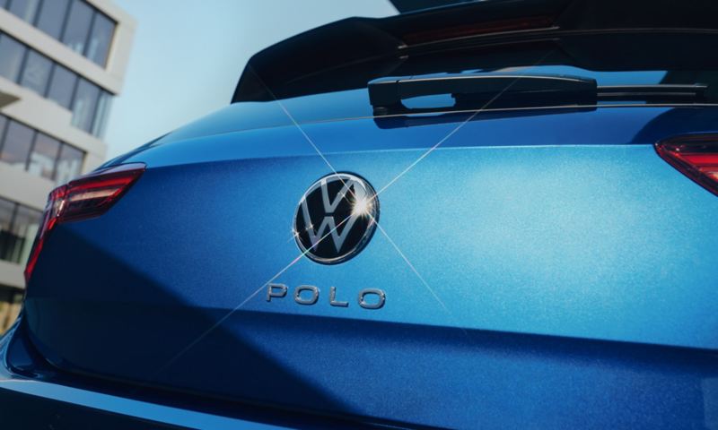 Detailansicht des VW Emblem und "Polo"-Schriftzugs auf der Heckklappe eines blauen Polo.
