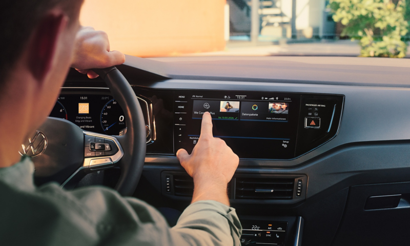 Vue de l'écran de la VW Polo avec fonctions Upgrades. Un homme est au volant et utilise l’écran.