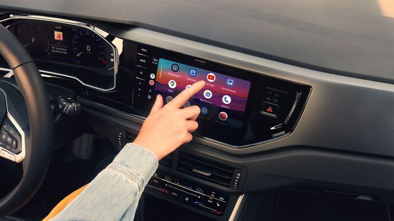 Display in the VW Polo showing Google Android Auto™. A hand is operating the display. 