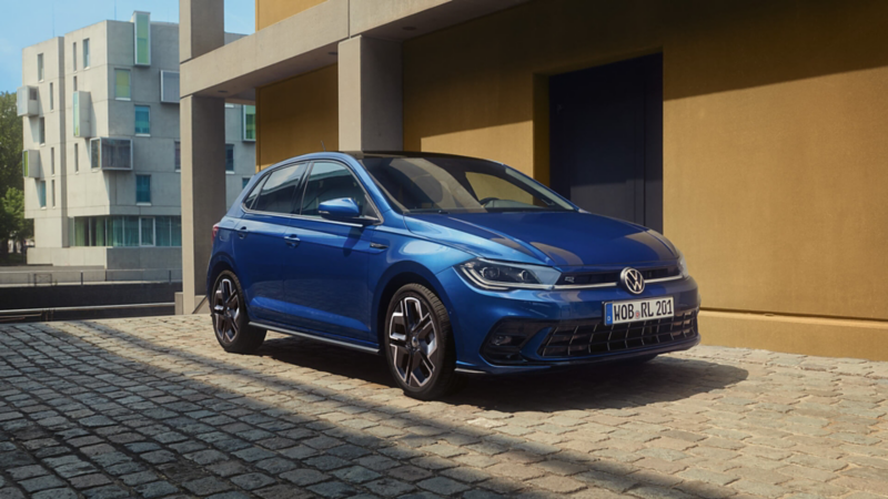 Une VW Polo bleue garée sur des pavés.