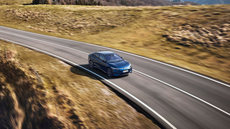 Ein blauer VW ID.7 fährt durch eine Berglandschaft.