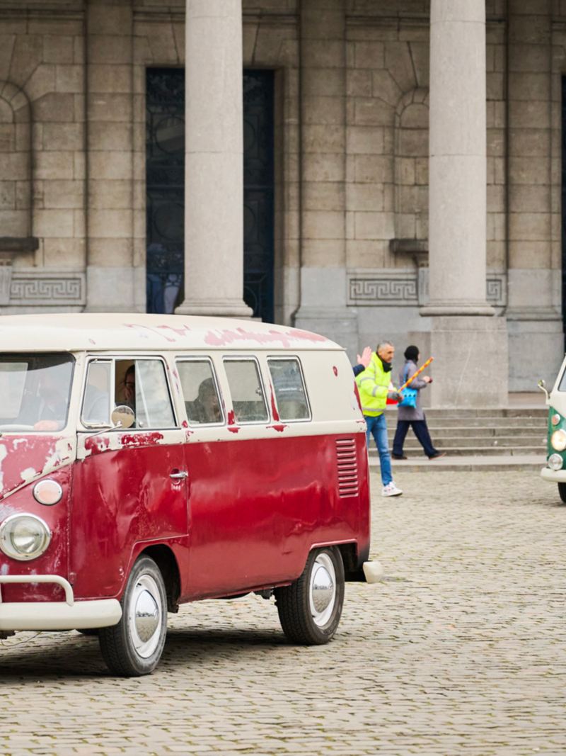 Een rode Volkswagen Bulli op de voorgrond met daarachter een groene Volkswagen Bulli