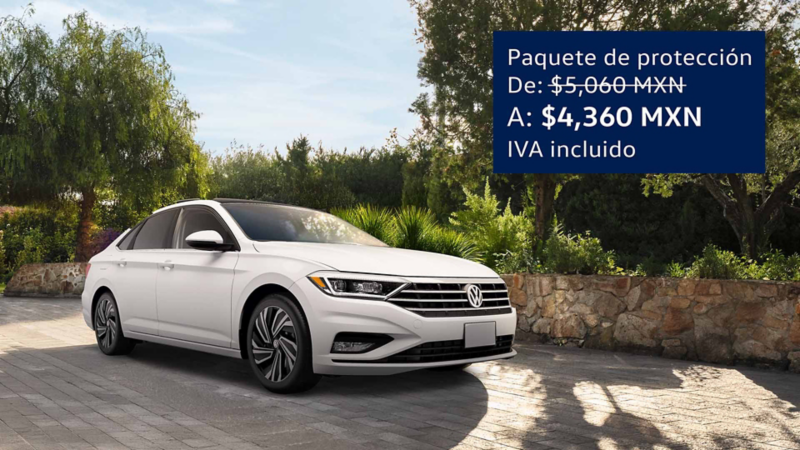 Auto seminuevo de Volkswagen en color blanco estacionado cerca de un jardín y barda de cantera.