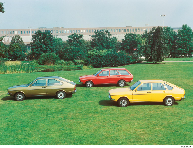 Three classic Volkswagen Passat models parked on a grassy field, shown in different colours and body styles as a heritage display