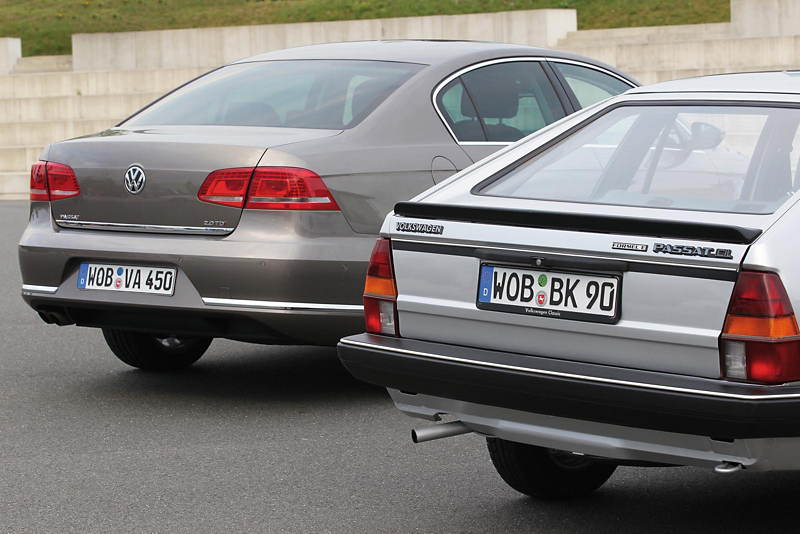 Rear three‑quarter view of two Volkswagen Passat models, showing an older estate version alongside a newer saloon design