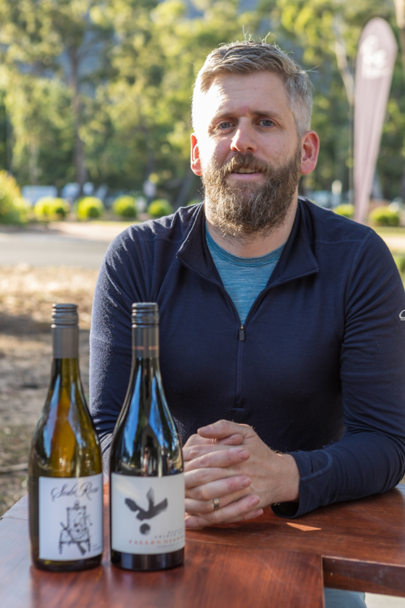Man sat outside with two bottles of wine in front of him