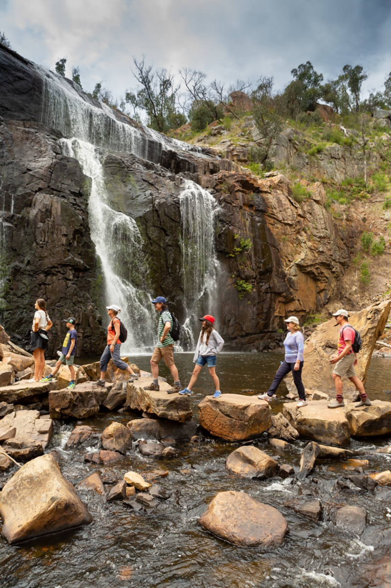 Image of a group walking across a rock formation by a waterfall