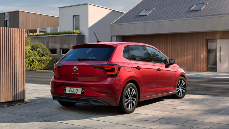 An old red VW Golf GTI and the new Golf GTI EDITION 50 in red are shown facing each other inside a factory hall.
