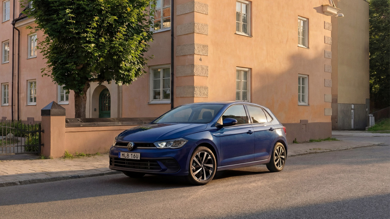 En blå Polo står parkerad längs en väg utanför ett stenhus