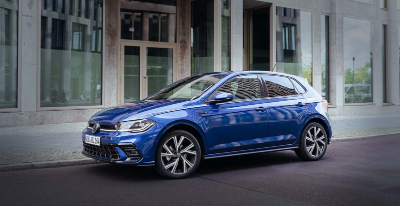 Niebieski Volkswagen Polo stoi przed budynkiem na ulicy