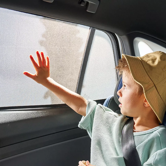 Child touching a window, but hes in the shade because of the sun blind