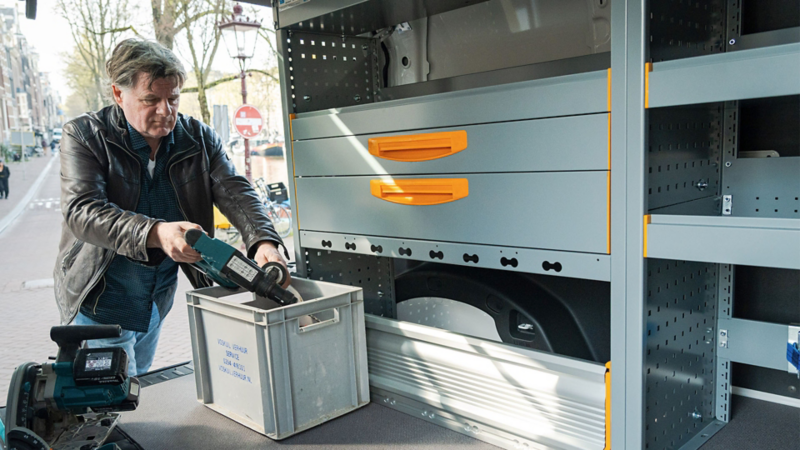 Een man pakt gereedschap uit een professioneel ingerichte ID. Buzz Cargo met ladesystemen in een binnenstad.