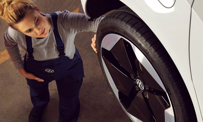 Un tecnico Volkswagen Service ispeziona il battistrada di uno pneumatico di un'auto Volkswagen.