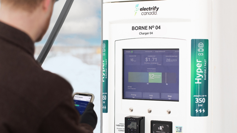 Homme utilisant un smartphone à une borne de recharge Electrify Canada.