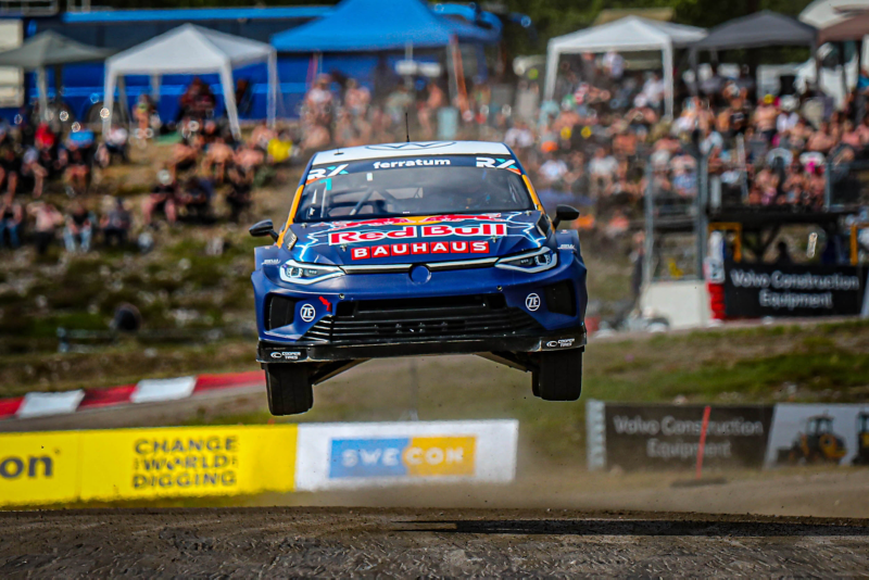 Rallybil i luften med publik i bakgrunden.
