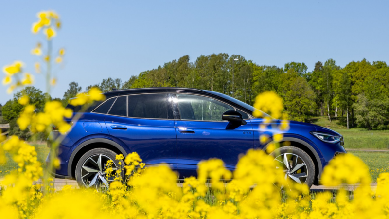 En blå Volkswagen ID.4 syns bakom gula rapsblommor
