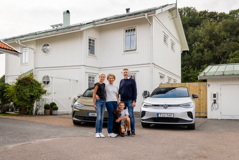Familjen Brunfelter står utanför sin vita villa med två elbilar från Volkswagen parkerade på uppfarten.