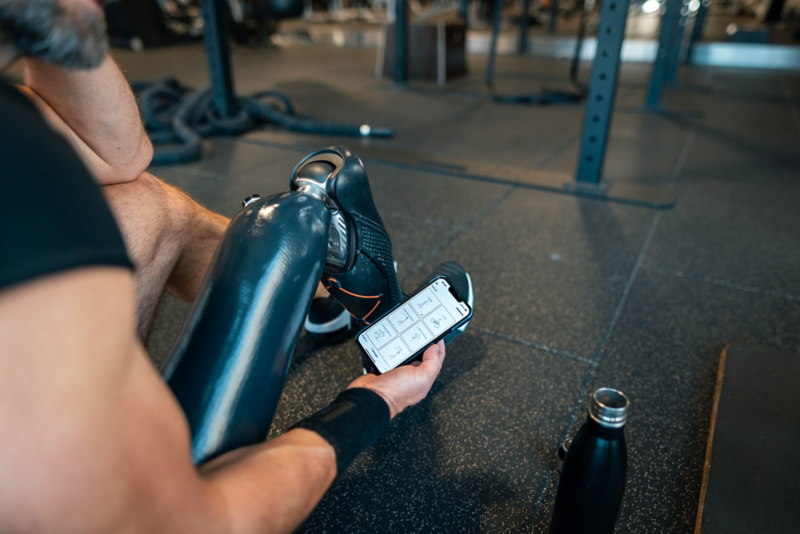 Paragolfare med benprotes använder mobilapp i gymmiljö