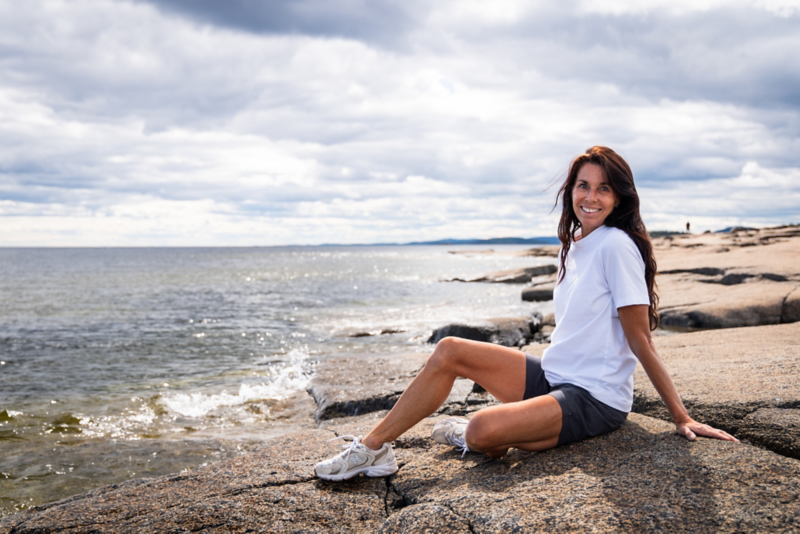 Magdalena Forsberg sitter på klippor vid havet.