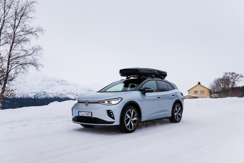 Volkswagen ID.4 kör på en snötäckt landsväg, i bakgrunden skymtas fjäll och en gul villa