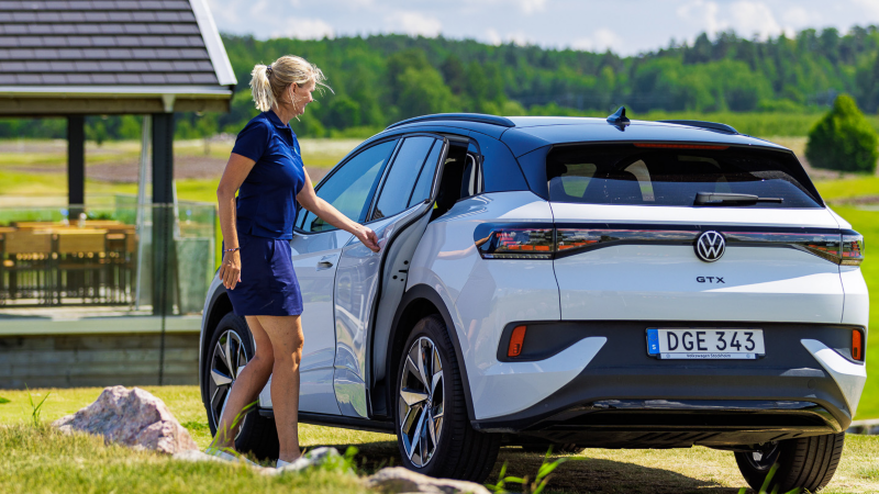 Vit Volkswagen ID.4 står på en golfbana, Ulrika stänger vänster bakdörr