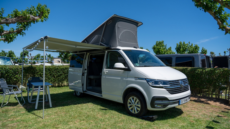 Un VW California con la puerta lateral abierta y el toldo tendido.