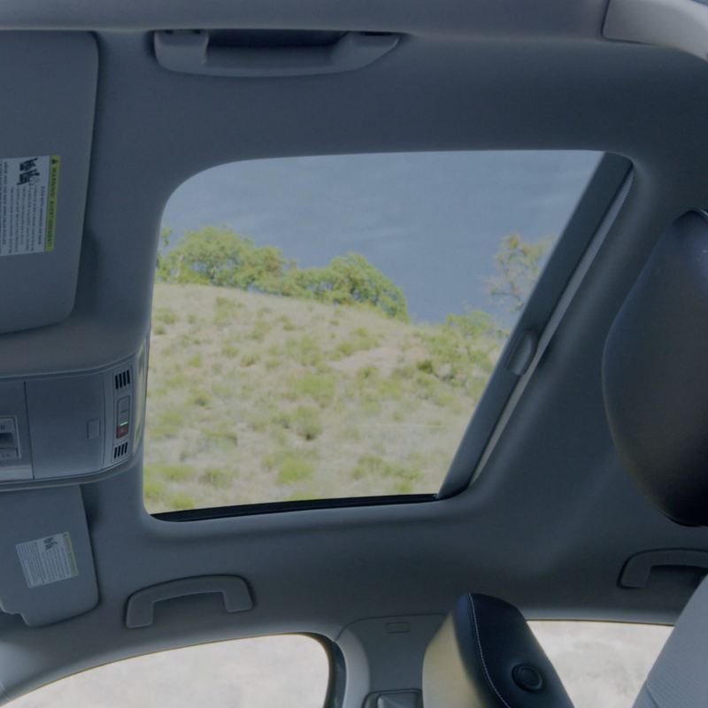 View through the Rail2Rail sunroof of the 2025 Volkswagen Jetta, showing the sky and greenery outside.