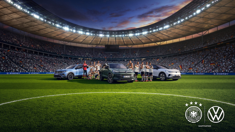 Drei Volkswagen Energy Sondermodelle stehen mit der Fußball Nationalmannschaft auf dem Rasen eines Stadions.