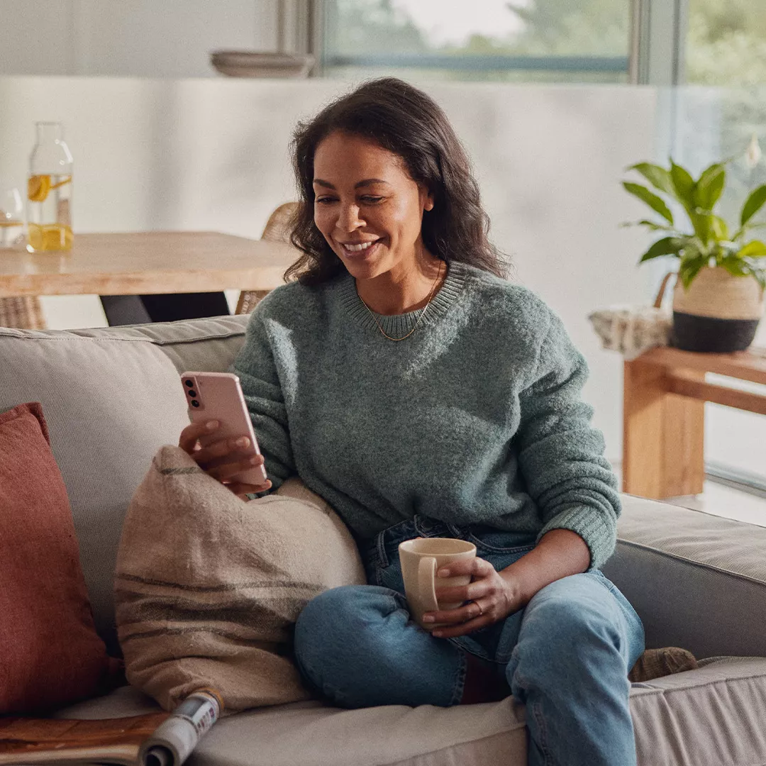 Eine Frau sitzt auf einem Sofa und bedient ihr Handy