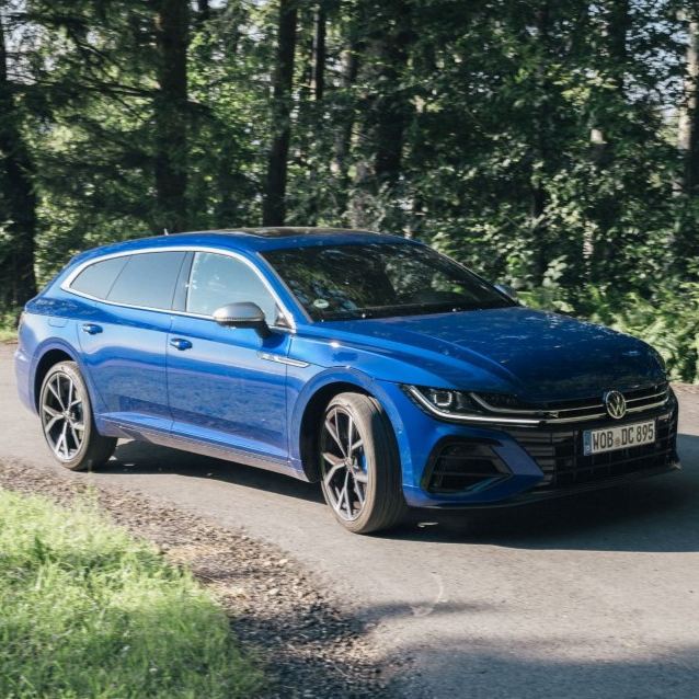 A blue VW Arteon Shooting Brake on a road in a forest.
