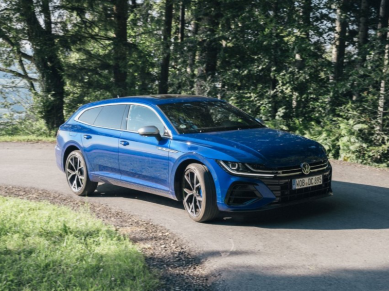 A blue VW Arteon Shooting Brake on a road in a forest.