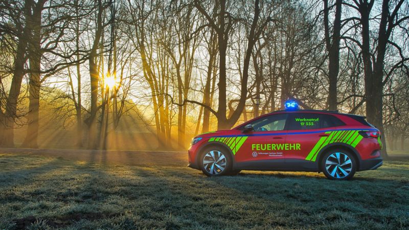 VW emergency vehicle in front of a forest, sun shining through the trees