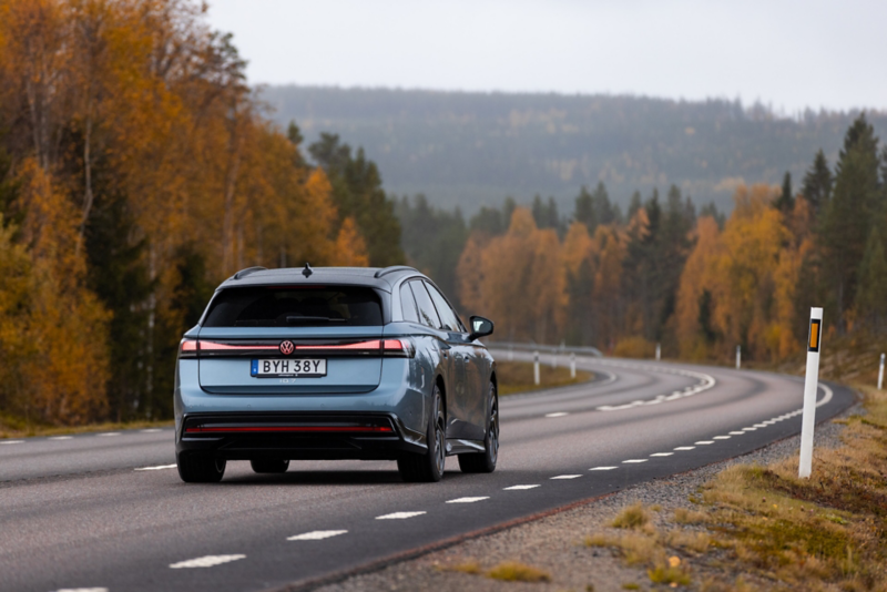 Ljusblå Volkswagen kör längs en landsväg en höstdag.
