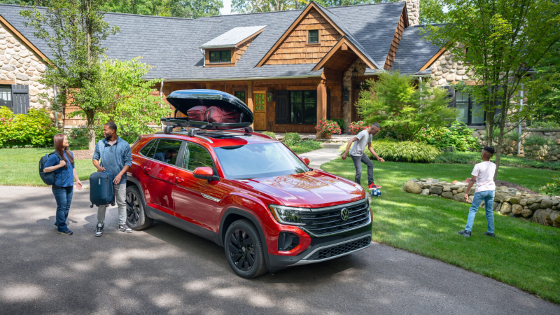 Volkswagen Atlas Cross Sport parked in the driveway of a cabin home with a family.