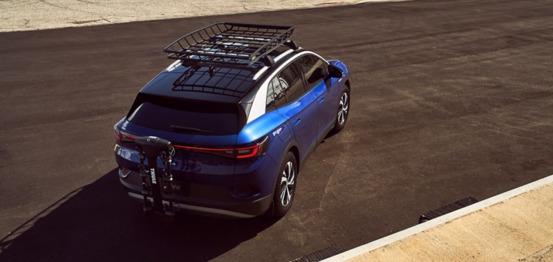 Volkswagen ID.4 parked on the road with a cargo basket on the roof and a bike rack at the rear of the vehicle. 