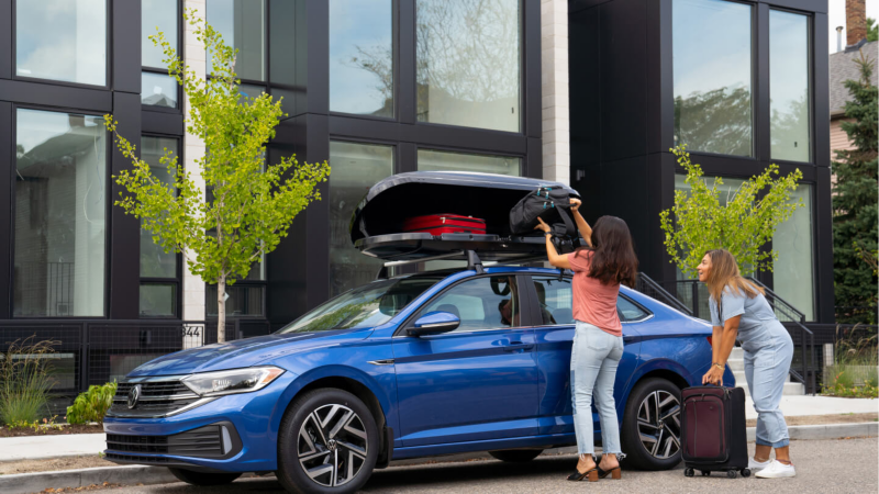 Volkswagen Atlas Cross Sport parked on city street being packed by owners. 