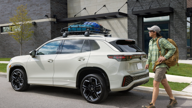 An owner walking with a backpack to the drivers side if their Tiguan. 