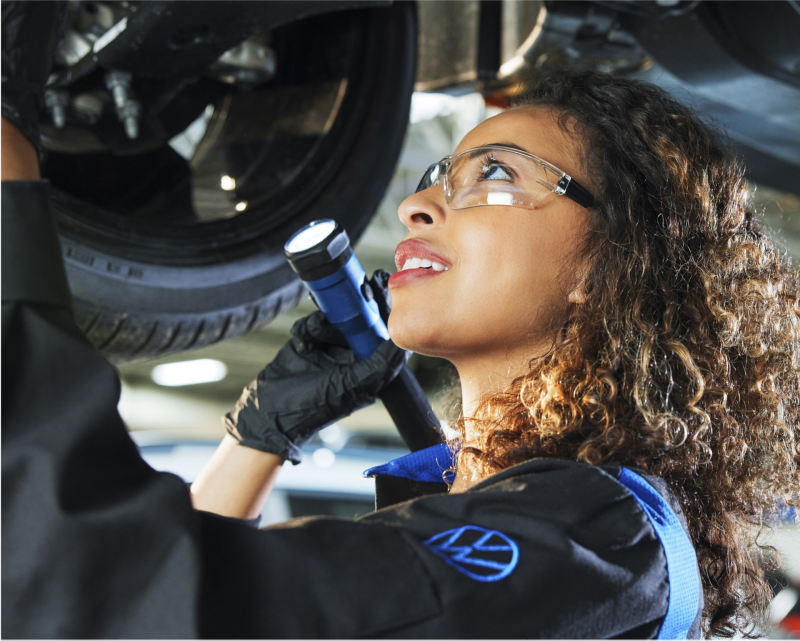 Técnico VW capacitado inspeccionando la rueda del vehículo.
