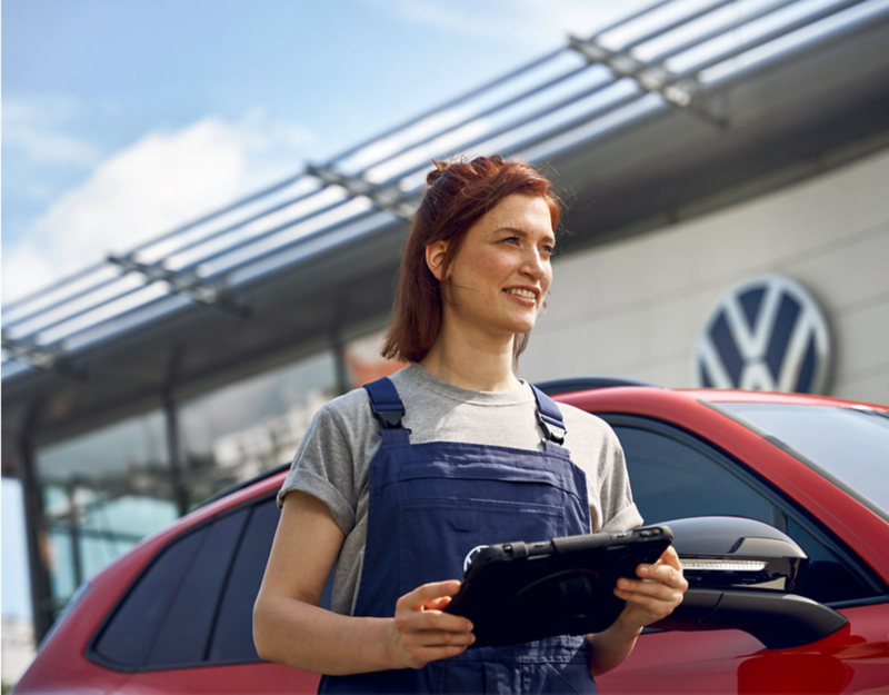 Certified VW technician inspecting red vehicle.