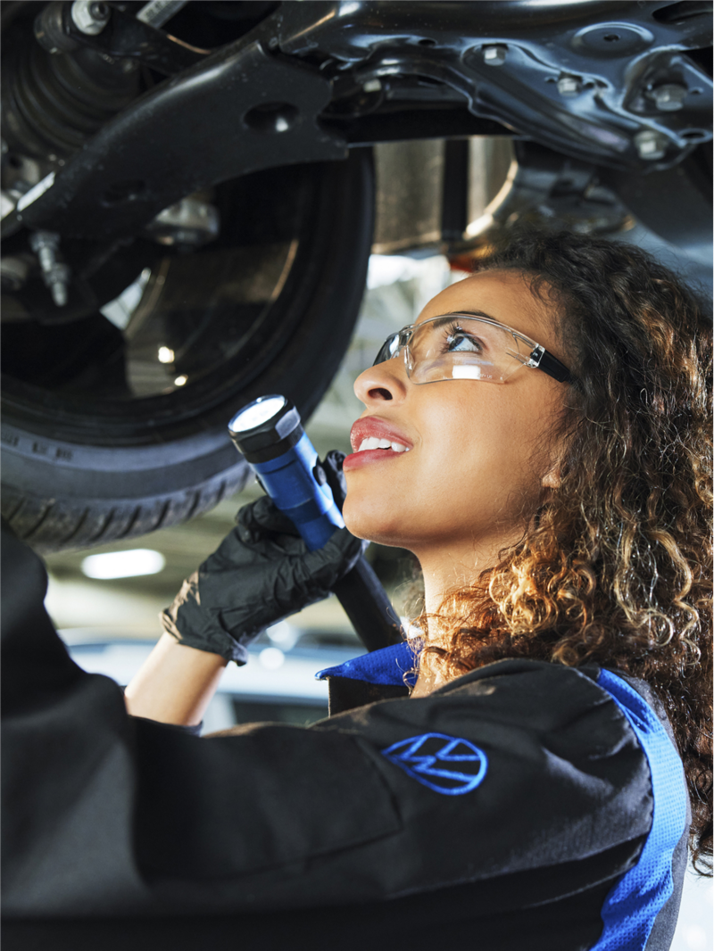 VW technician installing genuine VW brake parts on a vehicle.
