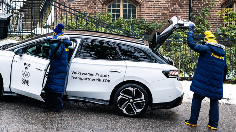 En vit VW ID.7 Tourer men texten "Volkswagen är stolt teampartner till SOK" på dörren. Två personer är vid bilen
